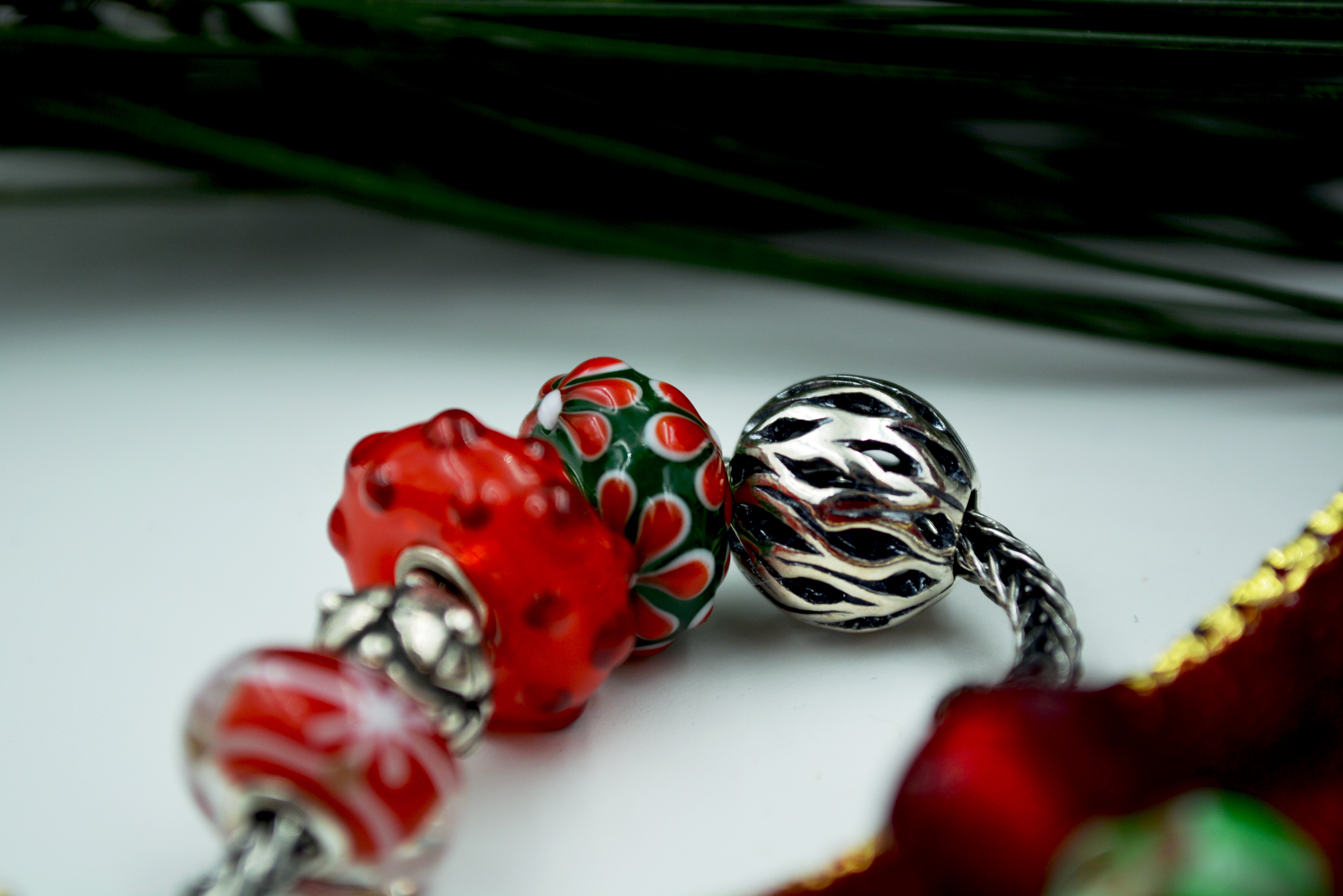 A selection of green and red glass beads and silver beads from the 2017 holiday Trollbeads release.